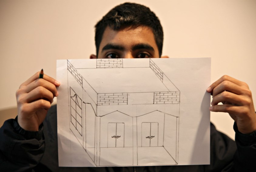 En ung gutt som bor i SOS-omsorgssenter i Athen viser frem tegningen han akkurat har laget. Den viser hans drømmehus, et trygt hjem for både han og familien. 
