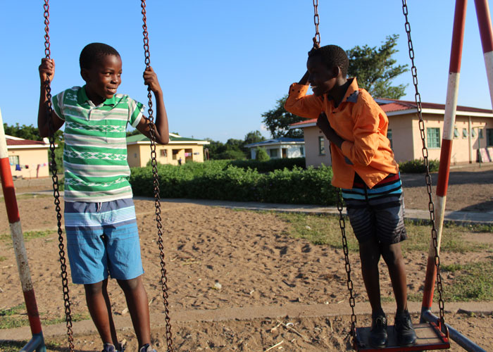 Barn i barnebyen i Ngabu leker sammen og en gutt blir løftet høyt i været.