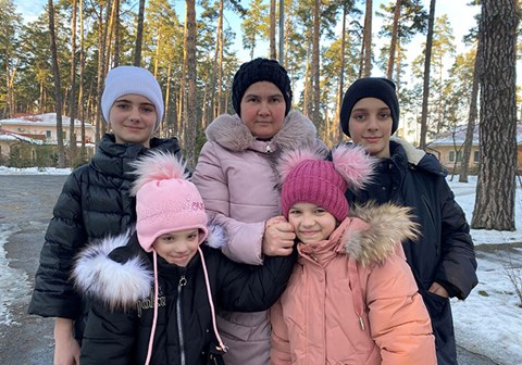 Valentyna og de fire barna står ute. Det er vinter og de har på seg lue og tykke jakker. Foto: SOS-barnebyer