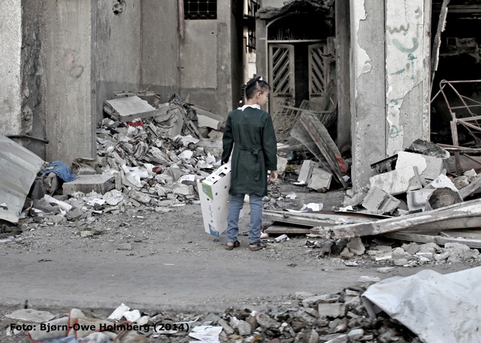 Jente står med ryggen til og ser på ruiner av et hus. Bildet er fra 2014. Foto: Bjørn-Owe Holmberg