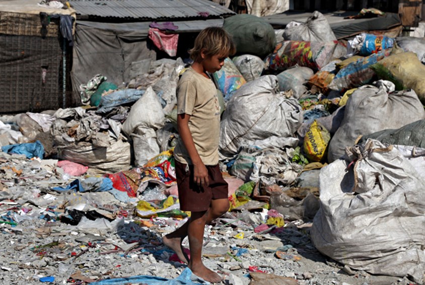 Gutt i shorts og t-skjorte, fra Manila, leter etter søppel som kan selges. Foto: Bjørn-Owe Holberg