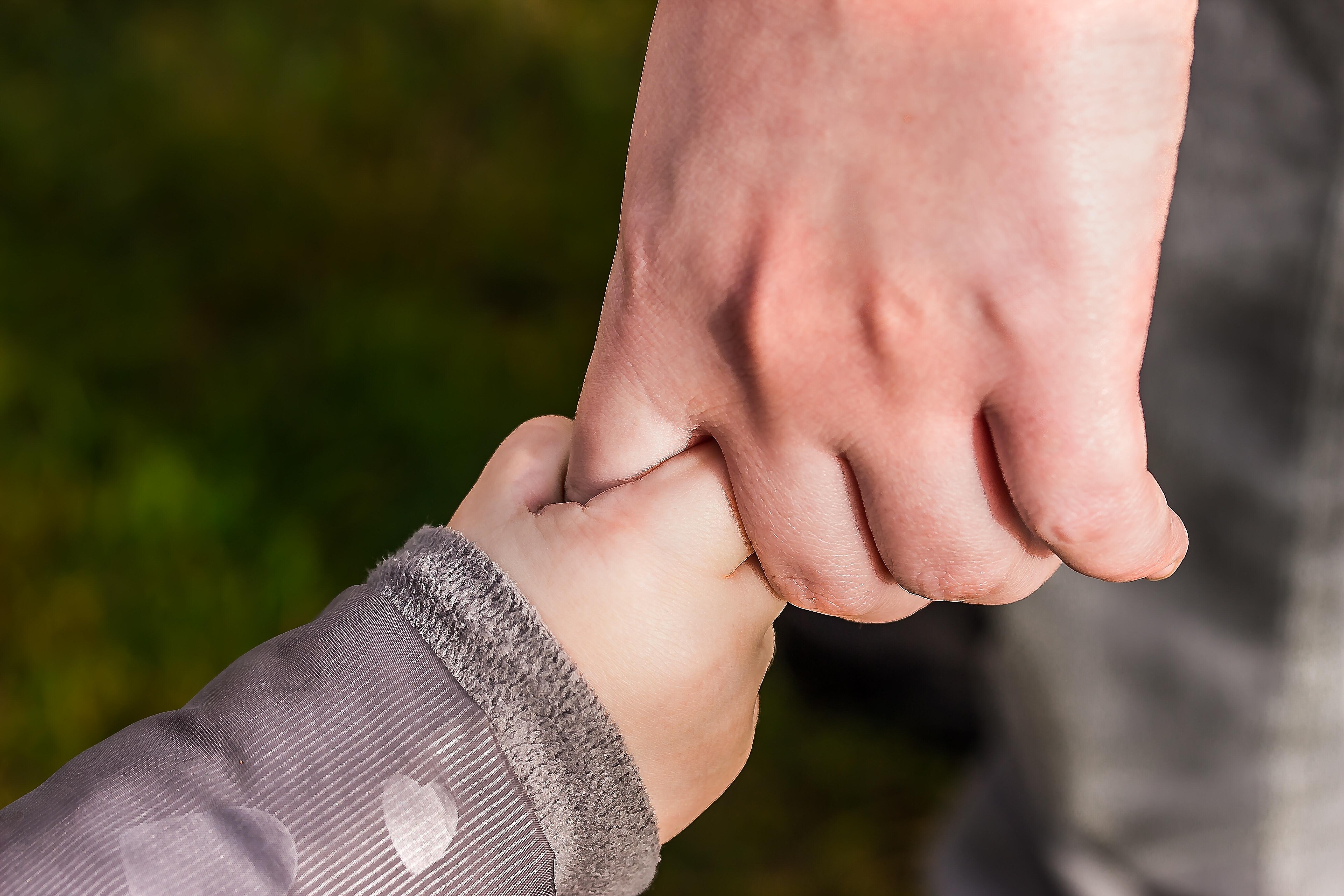 Vi er politisk nøytral og på barnas side. Uansett hvor barnet kommer fra. Bildet av en voksen hånd som holder et barnehånd- Foto: Pexels. 