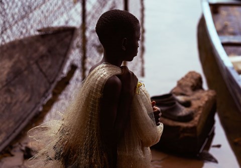 En gutt står på en brygge ved Lake Volta, over skulderen har han et fiskegarn. Foto: Henry KD