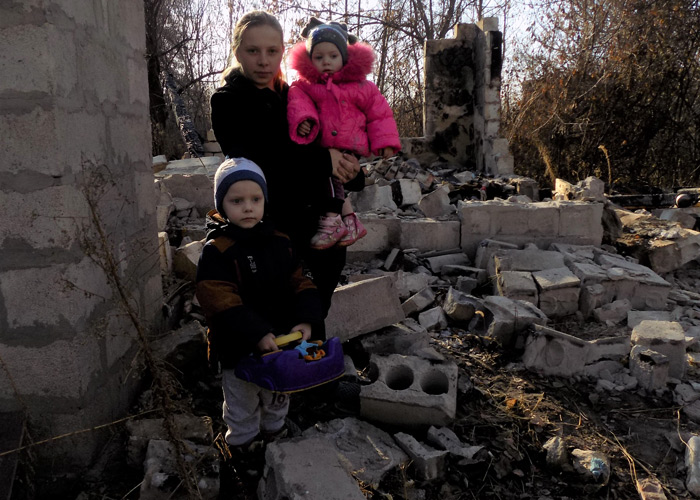 Mor og to barn foran huset som har brent ned. Foto: Maxim Shernet