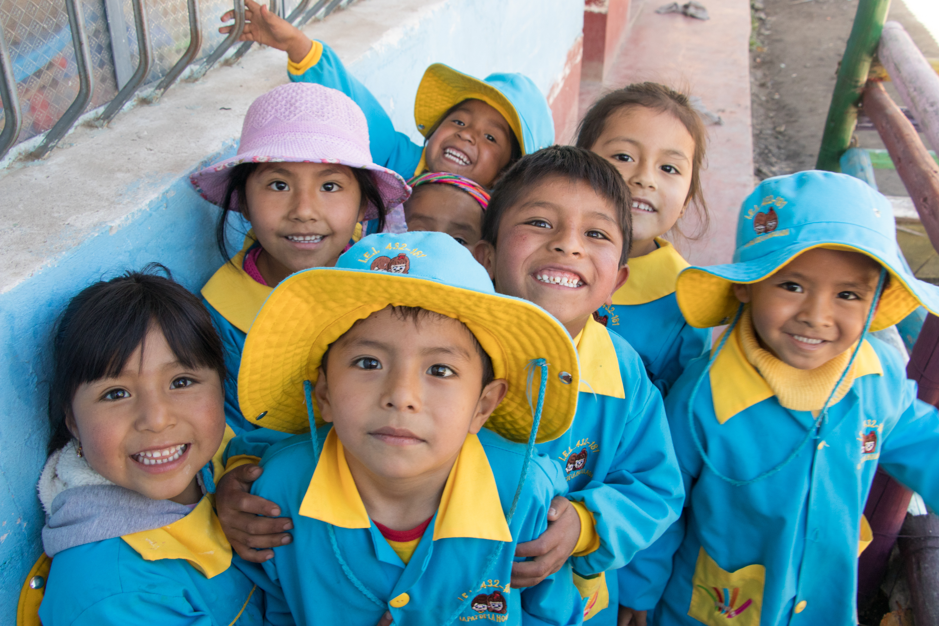 Åtte barn fra Peru i blå og gul barnehageuniform.
