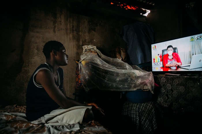En gutt sitter på senga i et mørkt rom og følger undervisningen via TV. Foto: Alea Horst