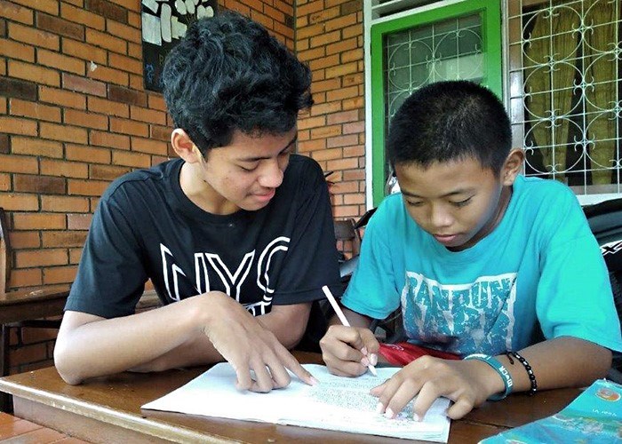 To sitter ved et bord og jobber med skolearbeidet. Fra SOS-barnebyer Indonesia. Foto: SOs-barnebyer