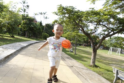 En liten gutt fra Vietnam i hvite klær og med en oransje ball.