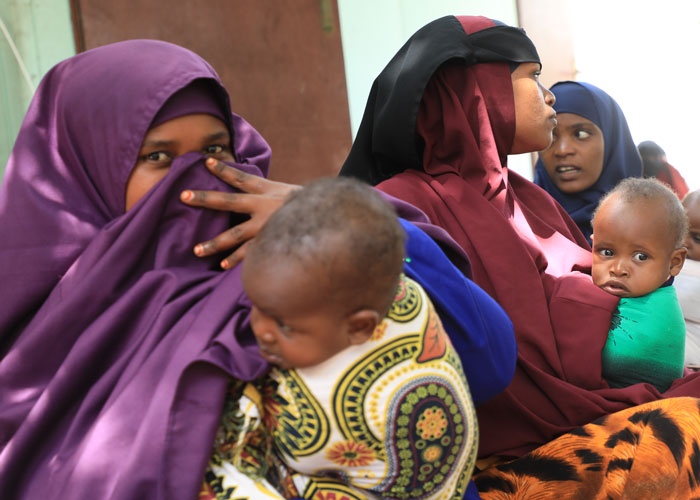 Kvinner sitter med de små barna sine på fanget i et flyktningmottak i Mogadishu. Foto: Sunshine Media