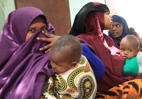 Kvinner sitter med de små barna sine på fanget i et flyktningmottak i Mogadishu. Foto: Sunshine Media