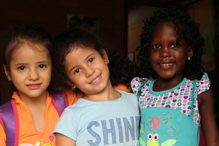 Tre glade jenter i en SOS-barneby i Colombia. Foto: Casta Noscuro