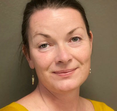 Anna Hamre er programrådgiver i SOS-barnebyer i Norge. Hun har mørkt blondt hår, og har på seg en gul genser. Foto: SOS-barnebyer