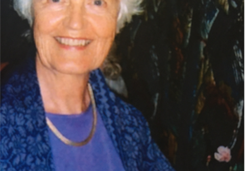 Portrettbilde av Berit Sørhus Tveter, som valgte å testamentere bort store deler av arven etter seg til SOS-barnebyer. Hun har blomstret jakke og blå bluse, og smiler til kamera. Foto: Privat
