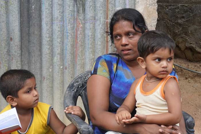 Gampolage Shanika Fonseka, mor til tre barn, sitter med den yngste sønnen på to år på fanget. Foto: Pearl Sandhu