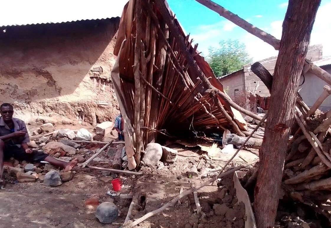 En mann sitter foran ødelagt hus. Foto: Cumbe Odete/SOS-barnebyer