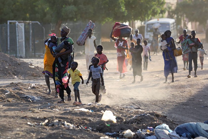 Sudan: Familier med barn flykter fra kampene. De går i en støvete gate. Foto: AFP