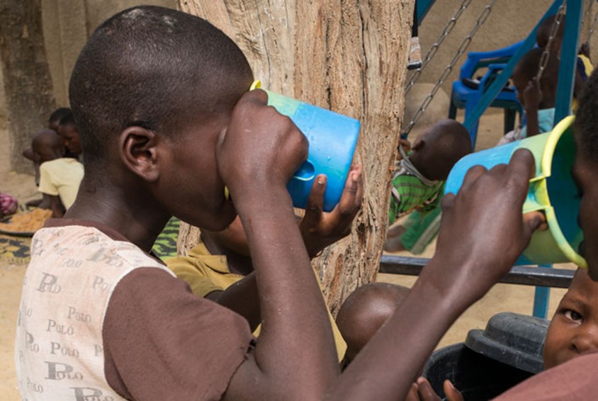 To gutter står i et barnevennlig område og drikker av store krus. Illustrasjonsfoto: Sylvain Cherkaoui