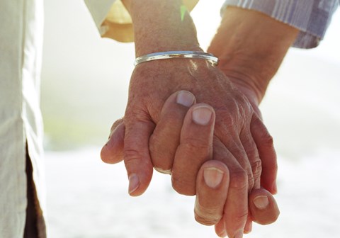 Elderly couple holding hands, close-up of hands