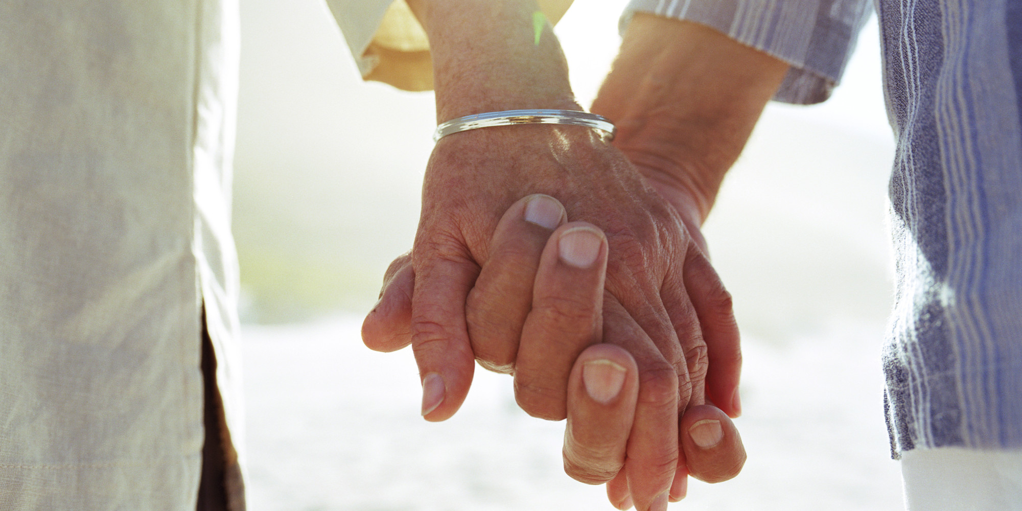 Elderly couple holding hands, close-up of hands