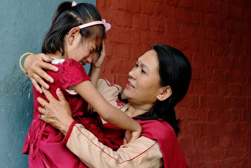 SOS-mamma trøster jenta ei jente som er lei seg. Fra en barneby i Nepal.