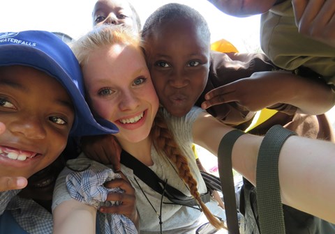 Tre barn og ungdom tar selfie i Zimbabwe, den til venstre har blå hatt, hun i midten har lyst hår.                               