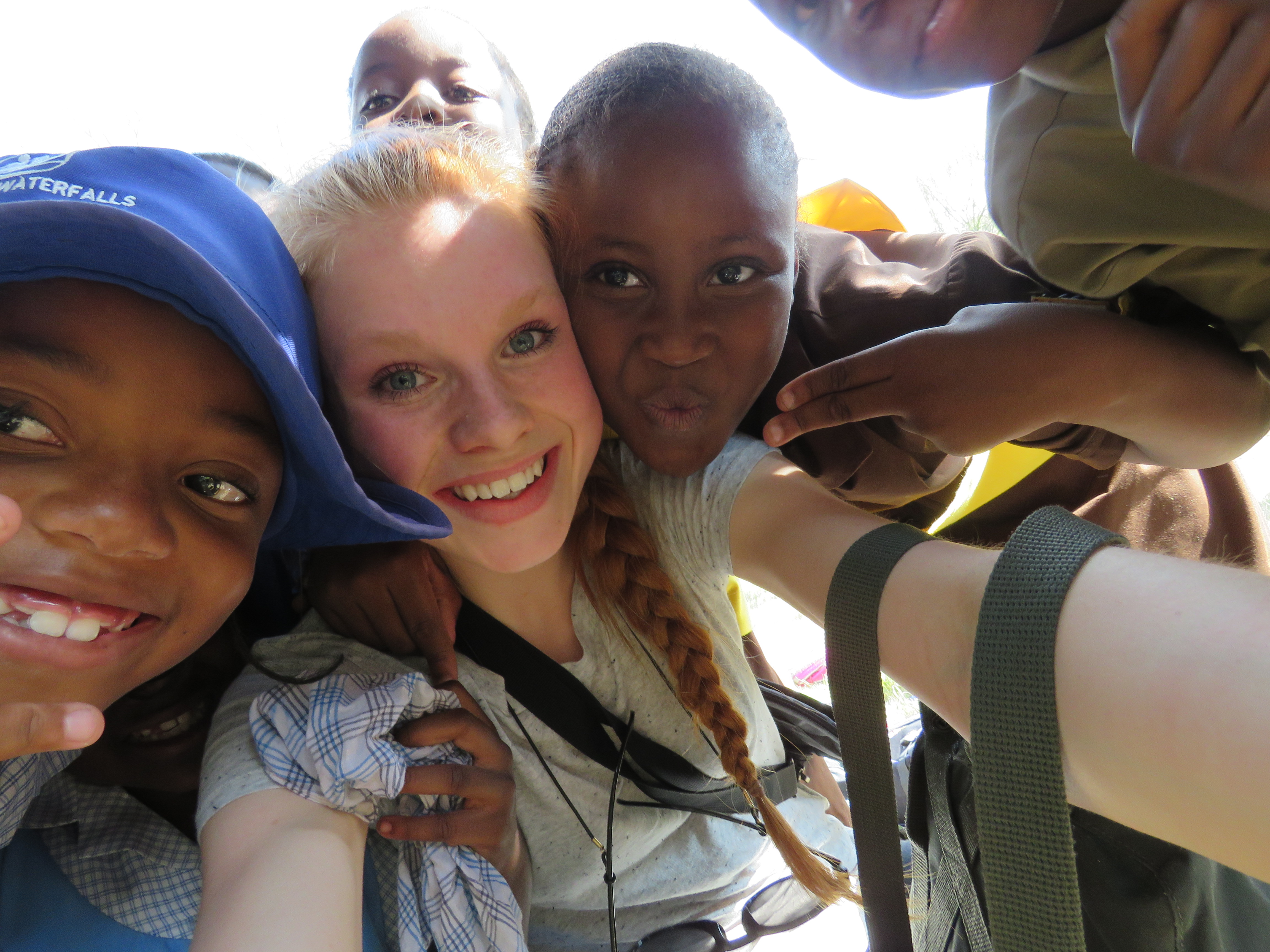 Tre barn og ungdom tar selfie i Zimbabwe, den til venstre har blå hatt, hun i midten har lyst hår.                               