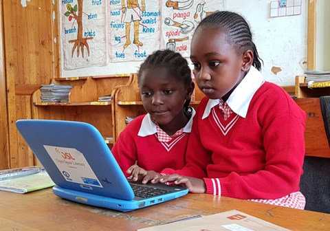 To jenter i røde skolegensere sitter ved en pult foran en PC. Fra skolen i SOS-barnebyer i Nairobi. Foto: Ahmed Mihaimeed